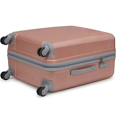 A hard-shell spinner suitcase in a muted dusty rose pink with gray accents, featuring a ribbed texture and four multi-directional wheels, shown on a plain white background.